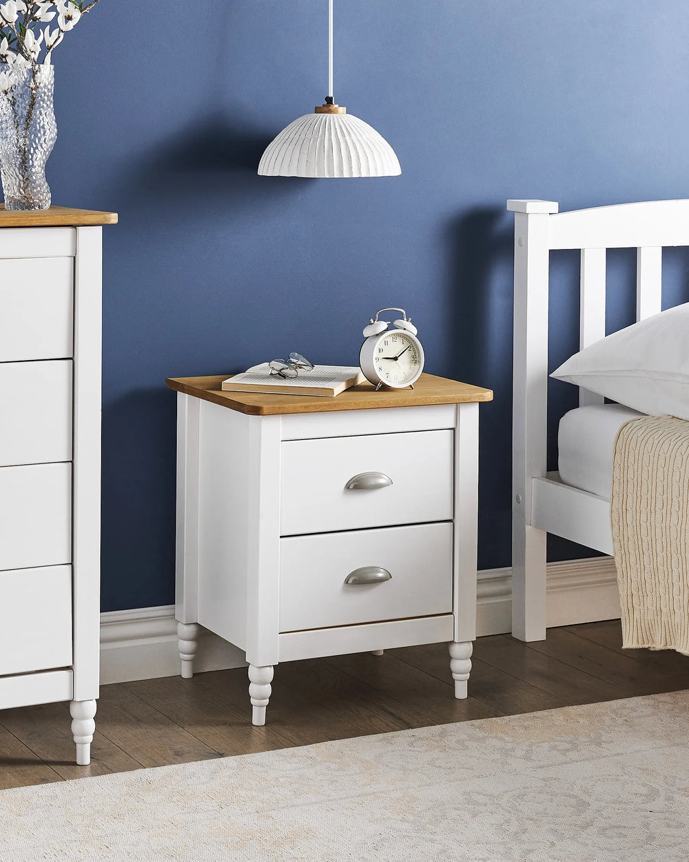 White nightstand with wooden top in a bedroom setting