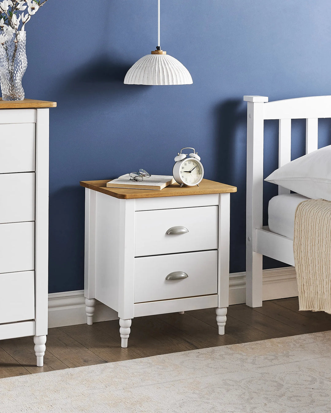 White nightstand with wooden top in a bedroom setting