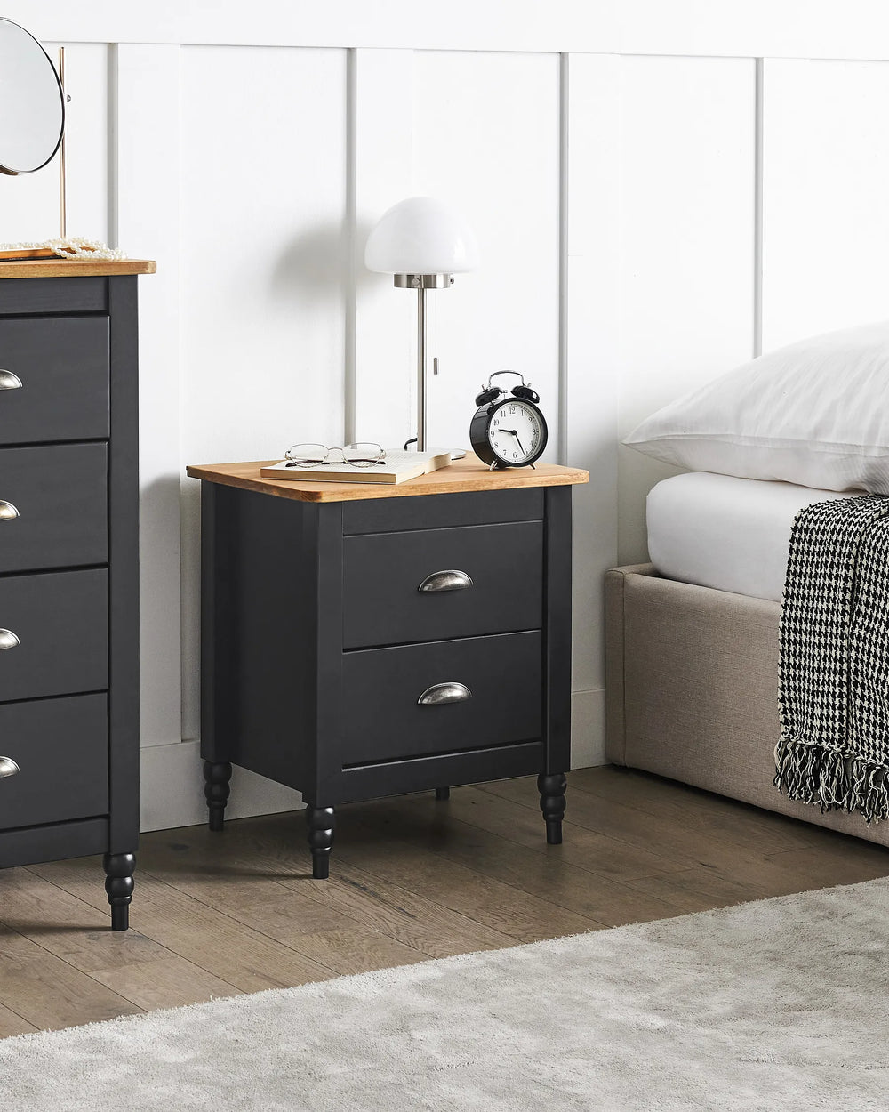 Black nightstand with wooden top in a bedroom setting