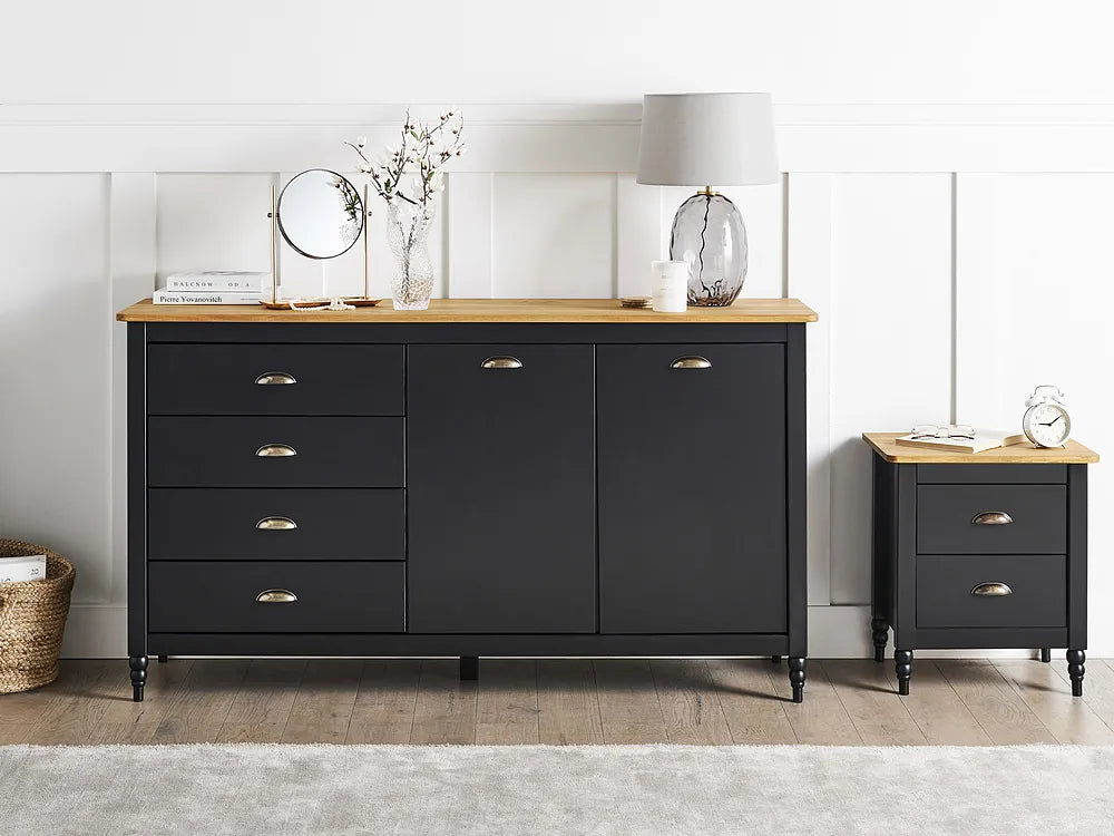 A black wooden sideboard cabinet with a light natural wood top and brass handles, shown in a styled room setting next to a matching nightstand.