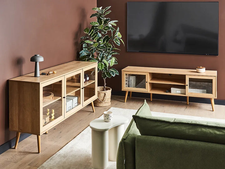 Modern living room with wooden TV stands, a green sofa, and a plant.