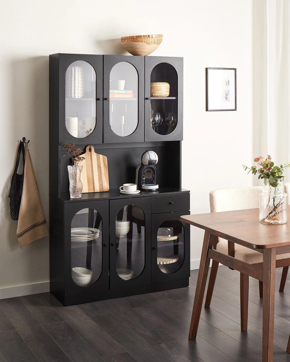 Black display cabinet with glass doors in a dining room setting.