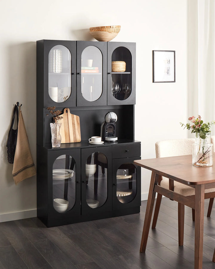 Black display cabinet with glass doors in a dining room setting.
