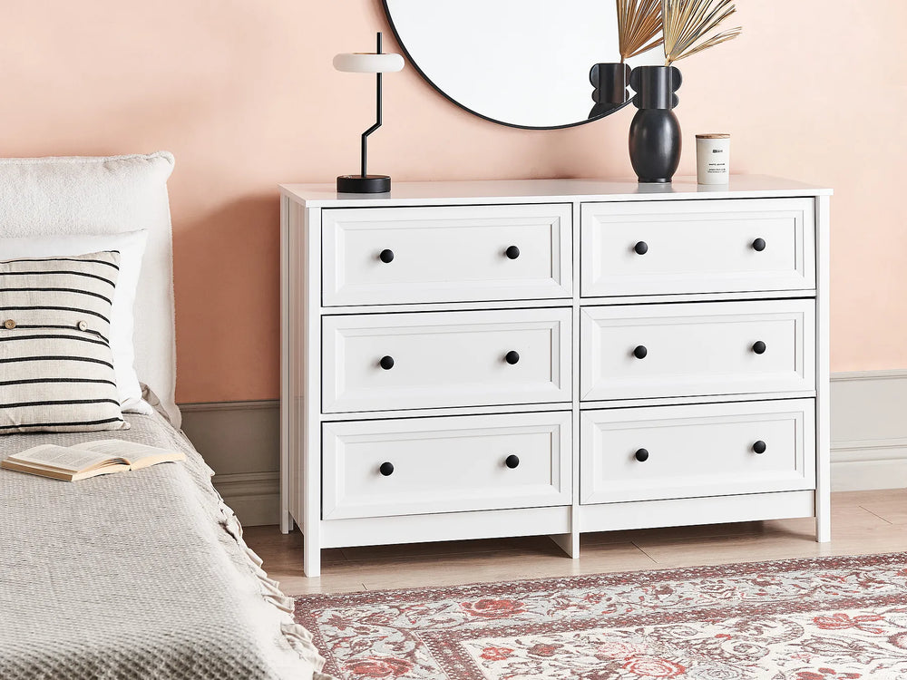 White dresser with six drawers in a bedroom setting.
