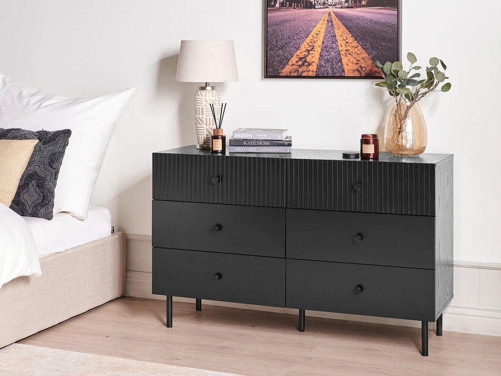 Black dresser with decorative items in a bedroom setting