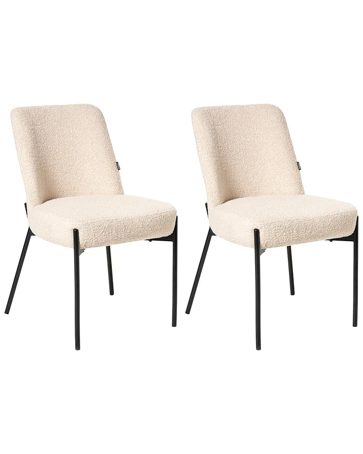 Two matching dining chairs with textured cream boucle upholstery and slim black metal legs, shown side by side on a plain white background.
