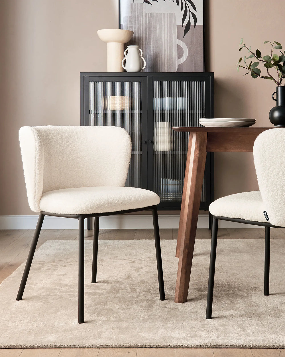 Dining room with beige chairs, wooden table, and decorative items on a shelf.