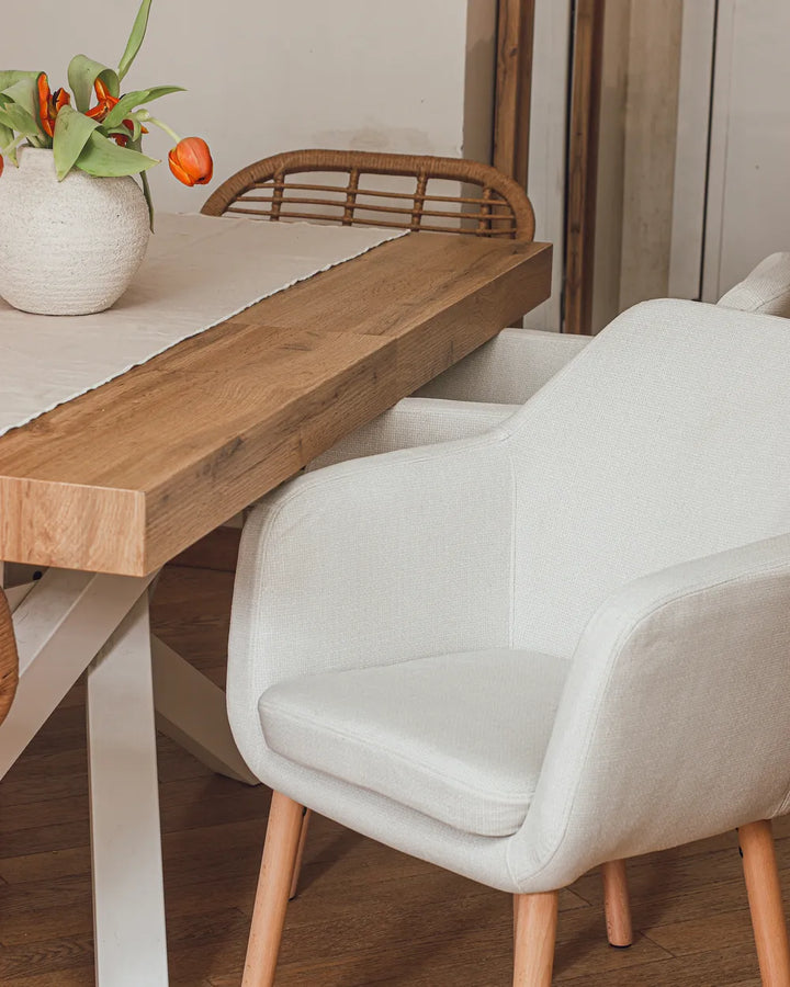 Dining table with a white chair and a vase of flowers on a wooden floor.