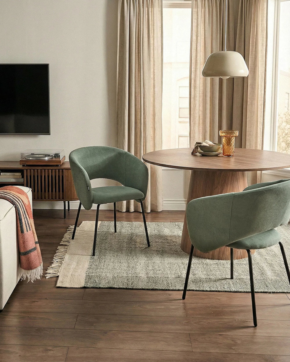 Modern living room with a round wooden table and green chairs.