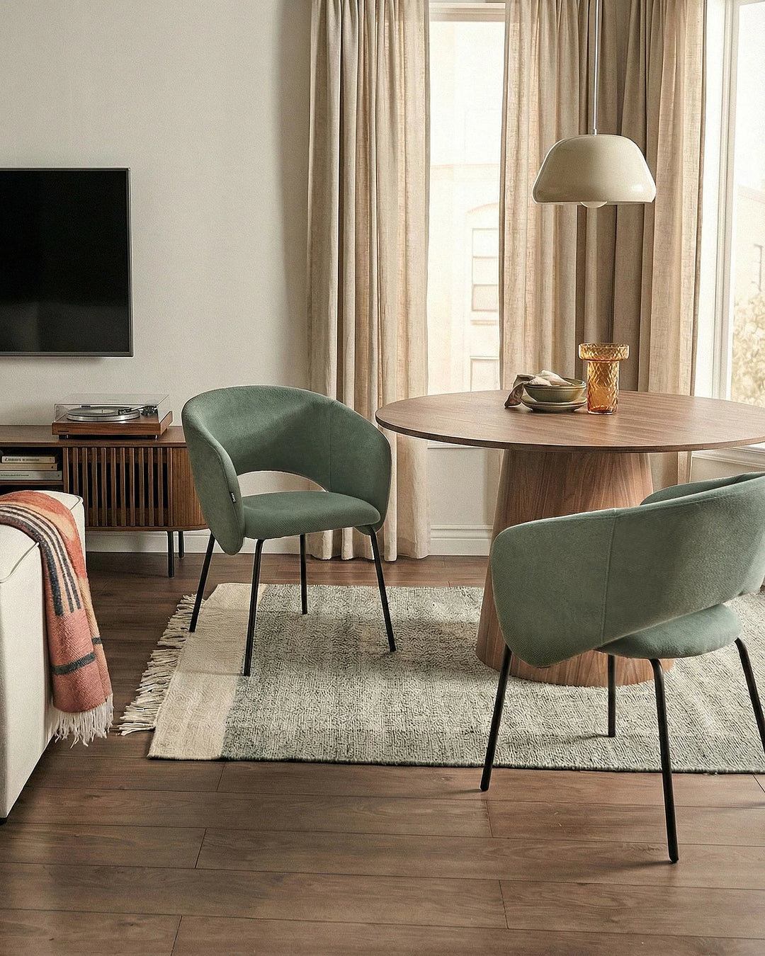 Modern living room with a round wooden table and green chairs.