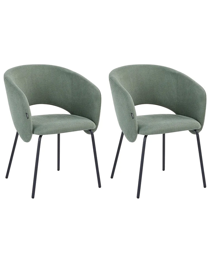 Two matching upholstered dining chairs with curved backs and seats in a muted sage green fabric, supported by slim black metal legs, shown on a plain white background.