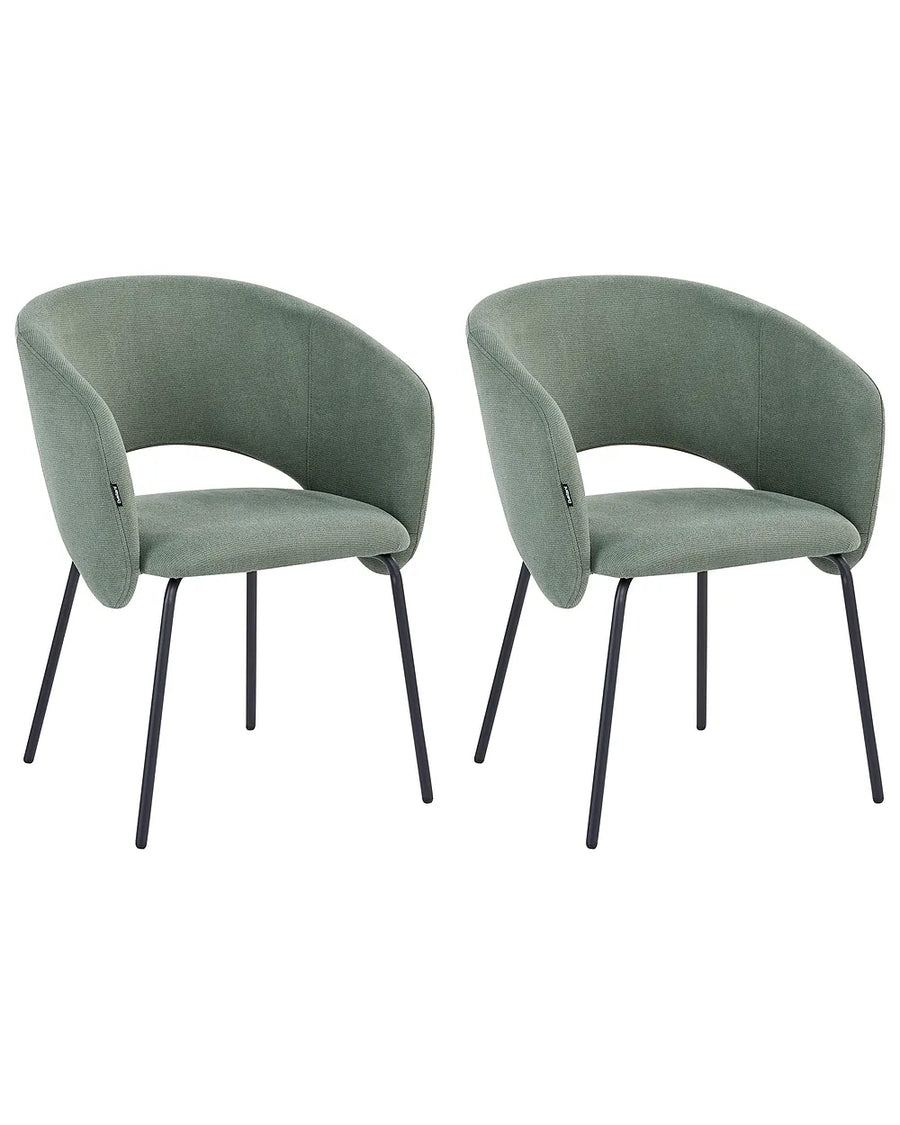 Two matching upholstered dining chairs with curved backs and seats in a muted sage green fabric, supported by slim black metal legs, shown on a plain white background.