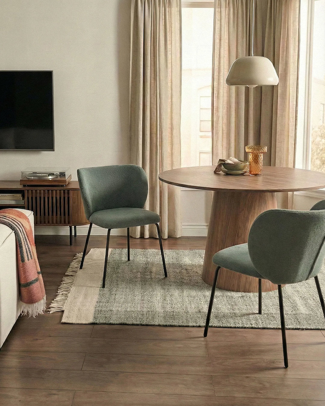 Modern living room with a wooden dining table and green chairs.
