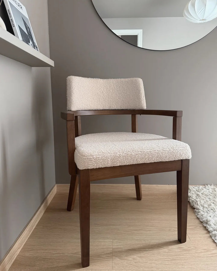 Chair with wooden frame and beige cushion in a room with a mirror on the wall.