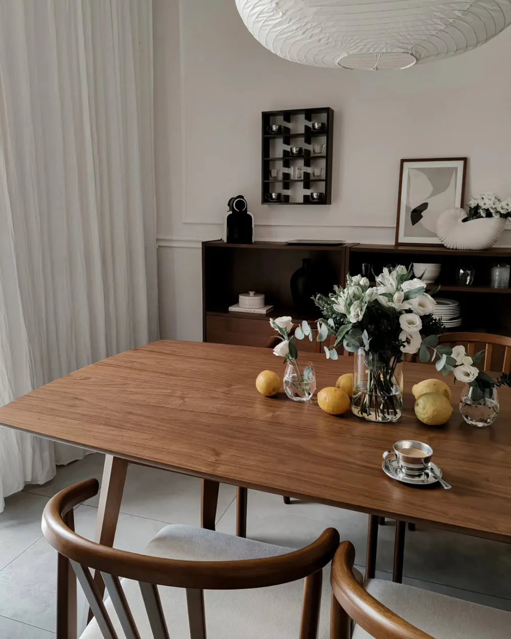 Dining room with a wooden table set for a meal, featuring fruits and flowers.