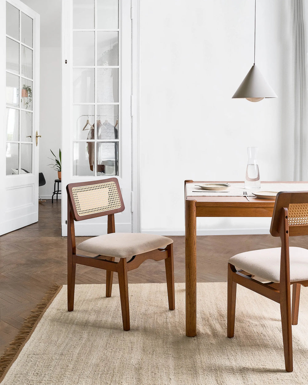 Dining room with wooden table and chairs in a bright, minimalistic setting.