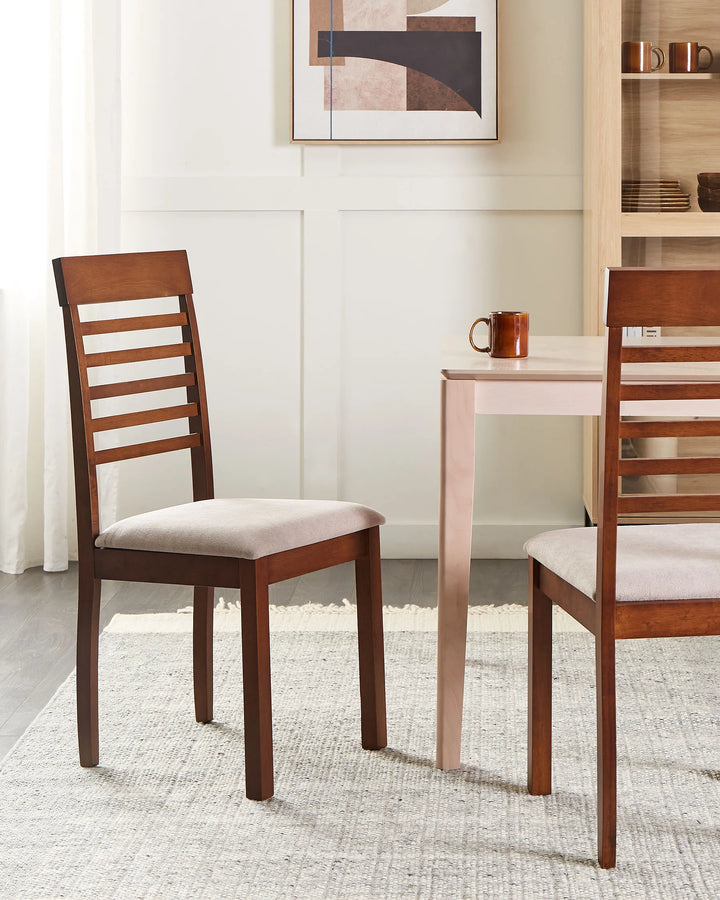 A wooden dining chair with a light beige upholstered seat is shown in a bright dining room next to a light wood table. A second matching chair is partially visible on the right.