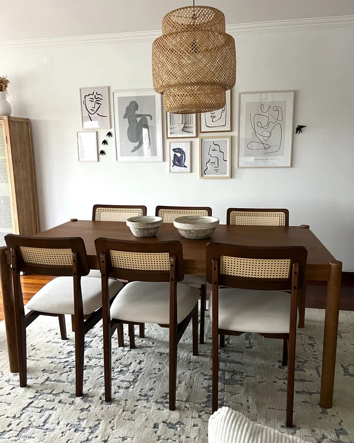Dining room with wooden table and chairs, wicker pendant light, and framed art on the wall.