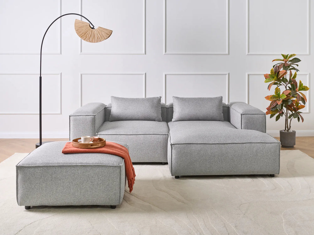 Gray sectional sofa with a matching ottoman in a modern living room setting.