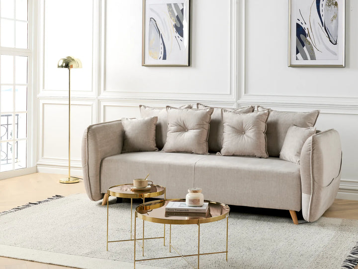 Beige sofa in a living room with gold coffee tables and abstract art on the wall.