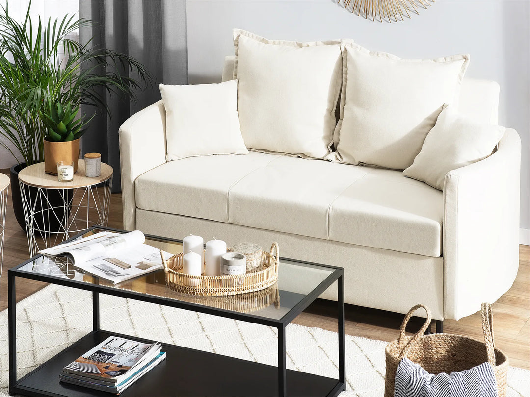 Beige sofa in a living room with a coffee table and decorative items.
