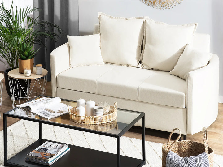Beige sofa in a living room with a coffee table and decorative items.