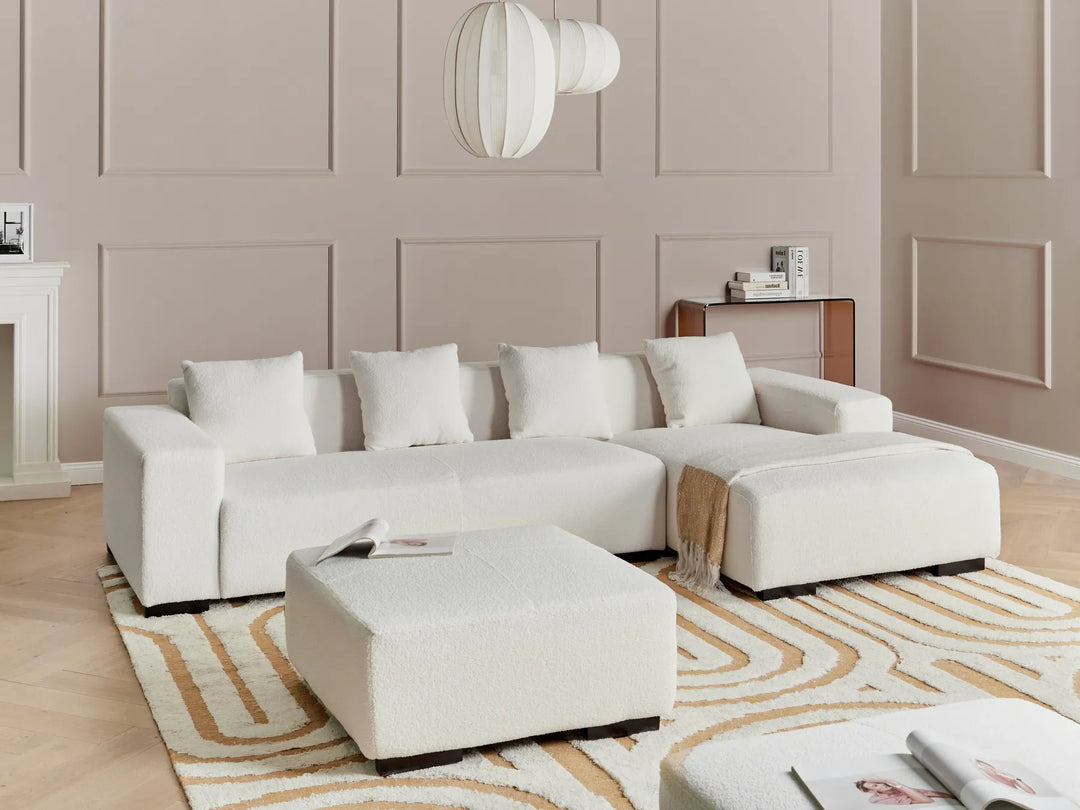White sectional sofa in a living room with a patterned rug and neutral walls.