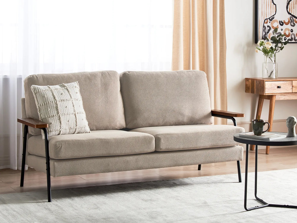 Beige sofa in a living room setting with a side table and decorative items.