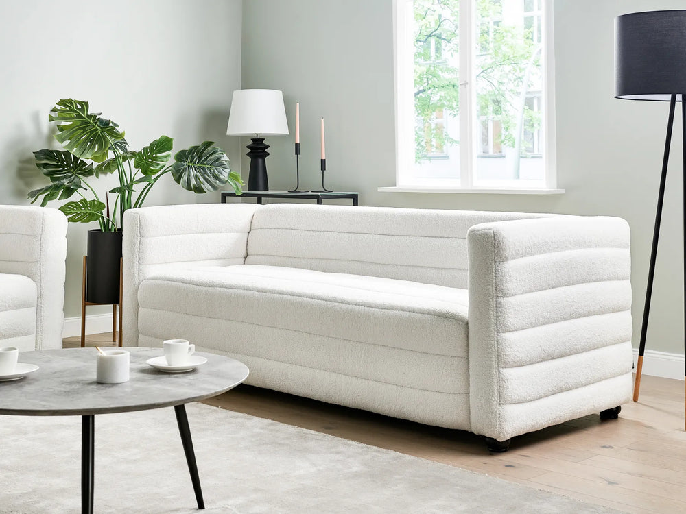 Modern living room with a white sofa, coffee table, and decorative elements.