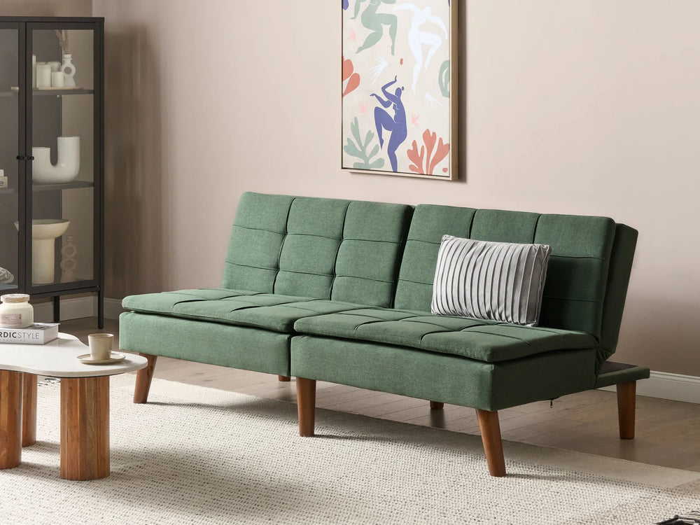 Green sofa in a living room with a coffee table and decorative items.