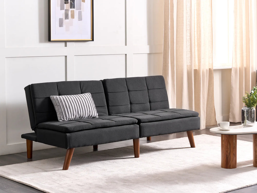 Gray futon sofa in a living room setting with a coffee table and decorative items.