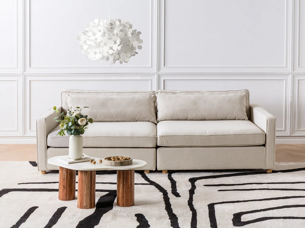 Beige sectional sofa in a living room with a coffee table and decorative items.