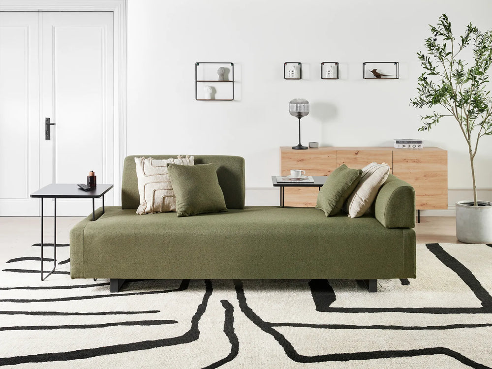 Green sofa in a modern living room with a white wall and decorative elements.