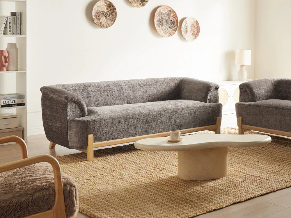 Modern living room with gray sofa, wooden armchair, and round coffee table.
