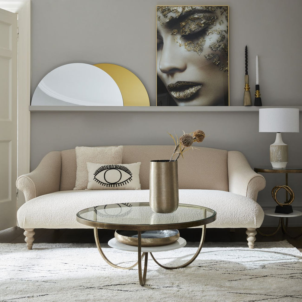 Living room with beige sofa, round glass coffee table, and wall art