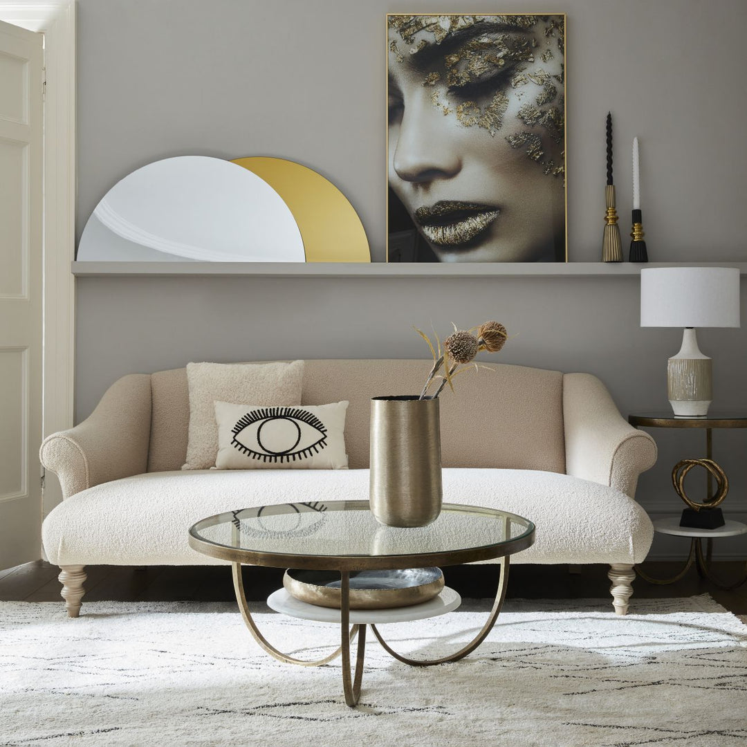 Living room with beige sofa, round glass coffee table, and wall art