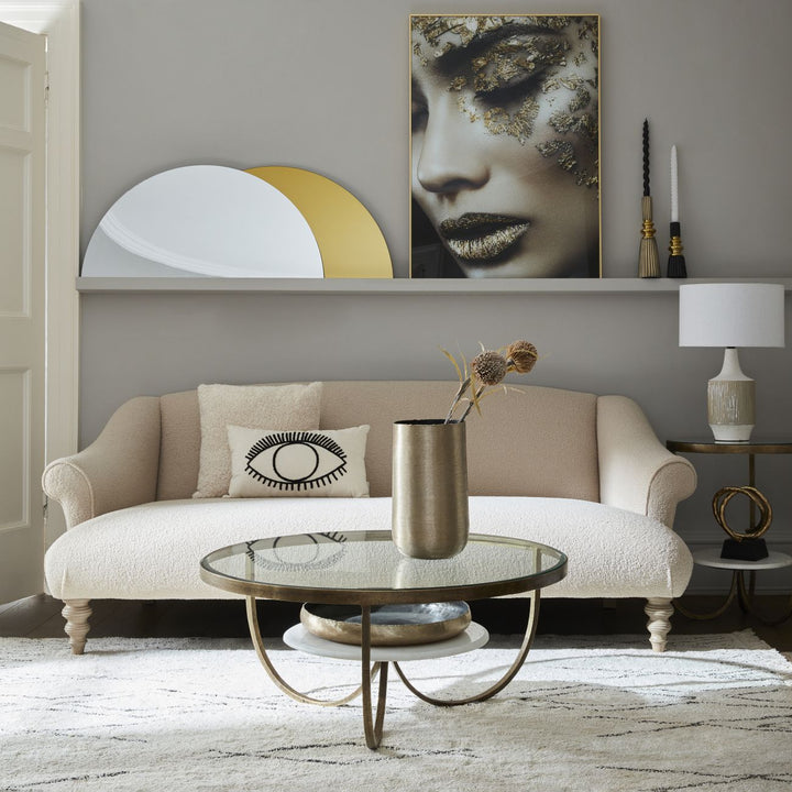 Living room with beige sofa, round glass coffee table, and wall art