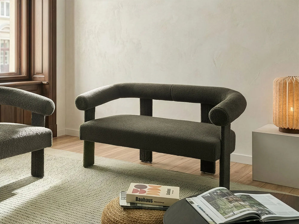 Modern dark gray sofa in a living room setting with a lamp and books on a table.