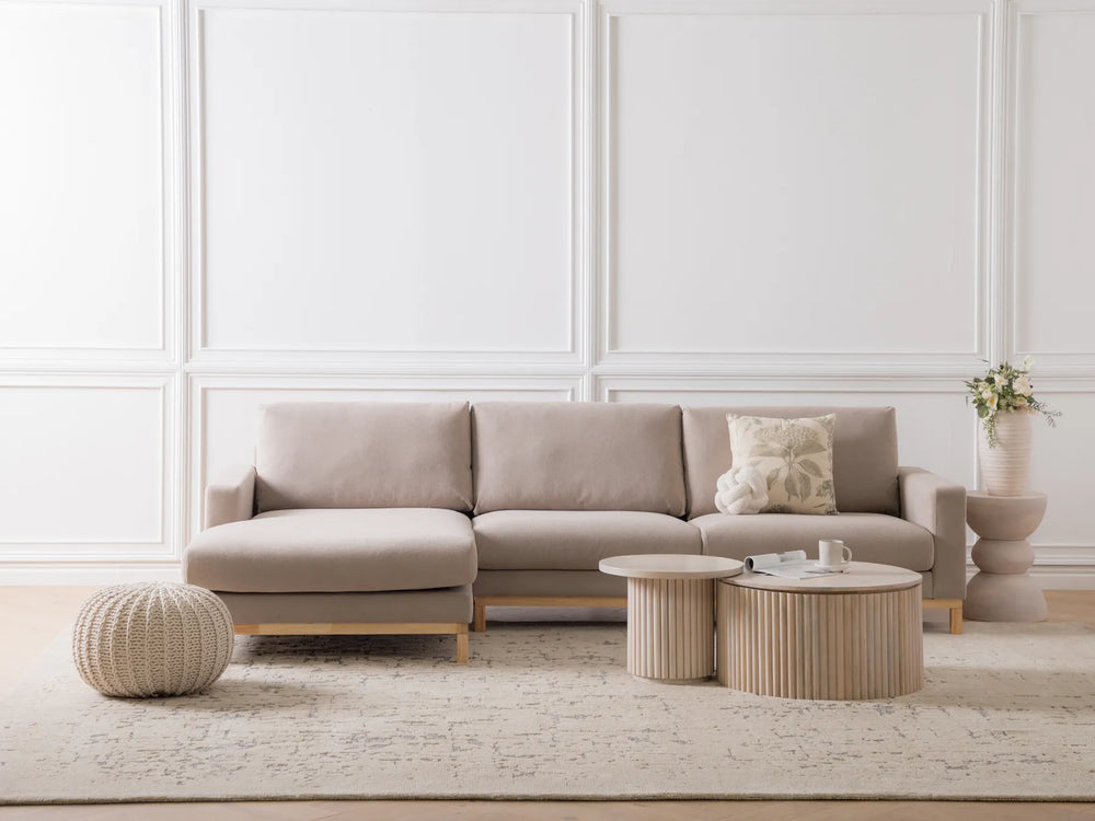 Beige sectional sofa in a modern living room with decorative pillows and side tables.