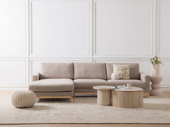 Beige sectional sofa in a modern living room with decorative pillows and side tables.