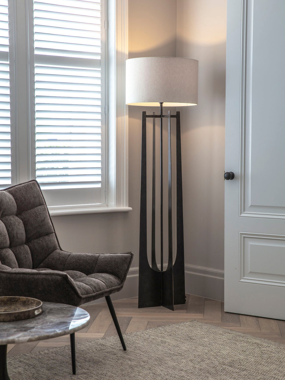 Modern living room with a gray armchair, round coffee table, and a tall floor lamp.