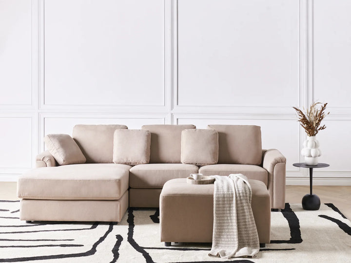 Beige sectional sofa in a living room with a white wall and decorative elements.