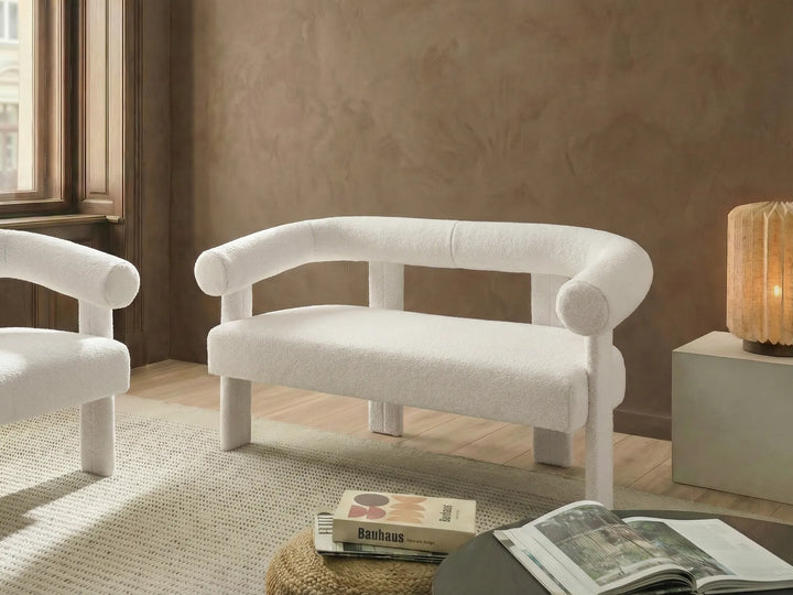 White armchair in a room with a textured wall and a lamp.