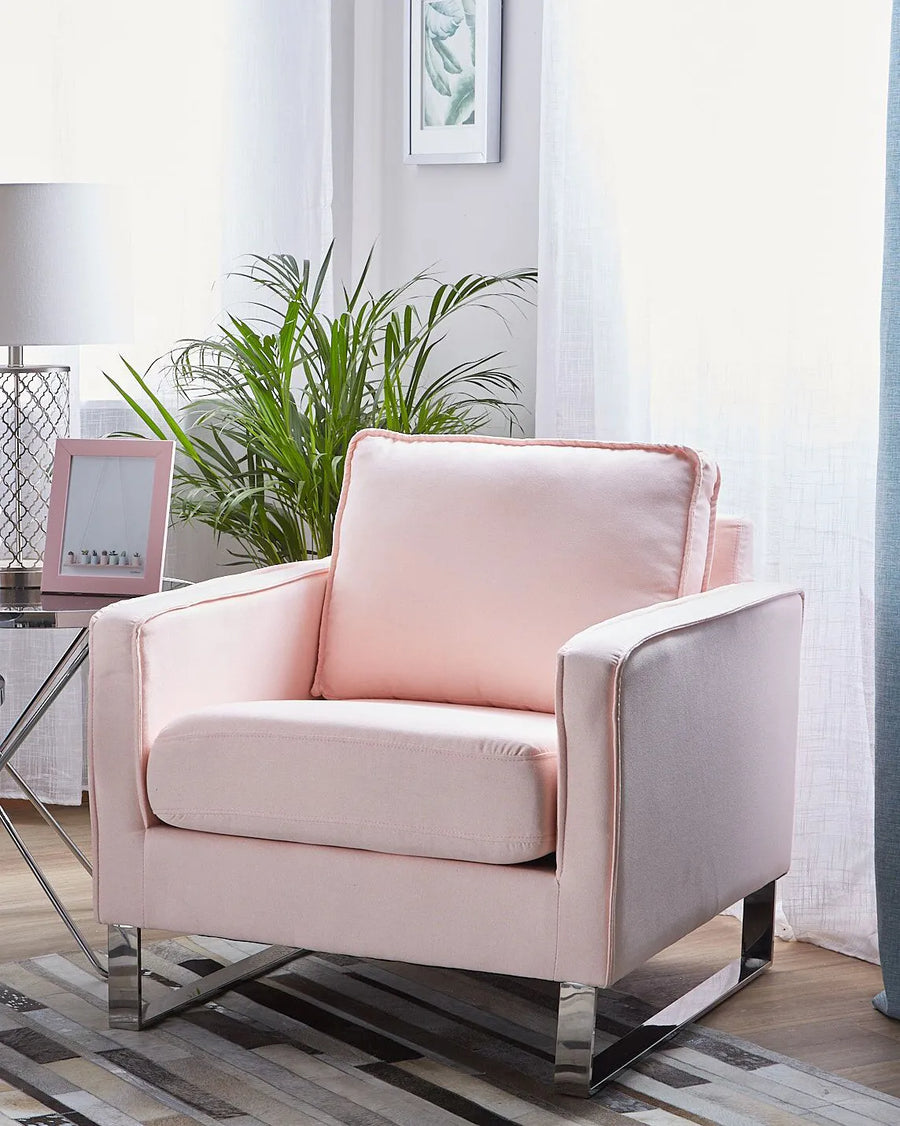 Pink armchair in a living room setting with plants and a lamp.