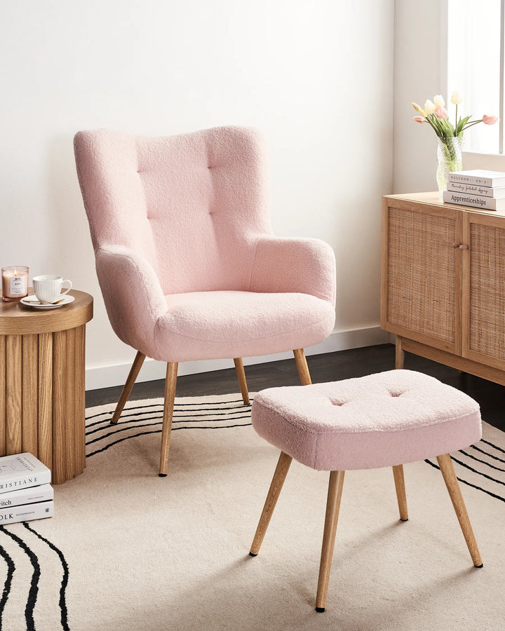 Pink armchair and ottoman with wooden side table and cabinet in a room.