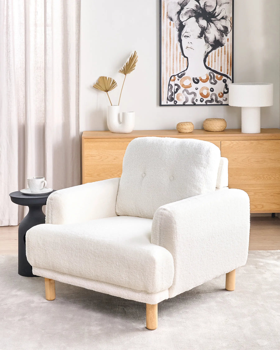 White armchair in a living room setting with a wooden sideboard and decorative items.
