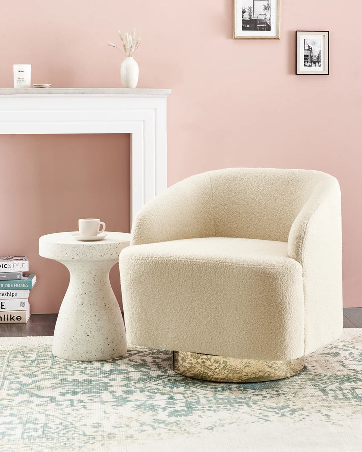 Beige armchair in a living room with a pink wall, white fireplace, and small table.