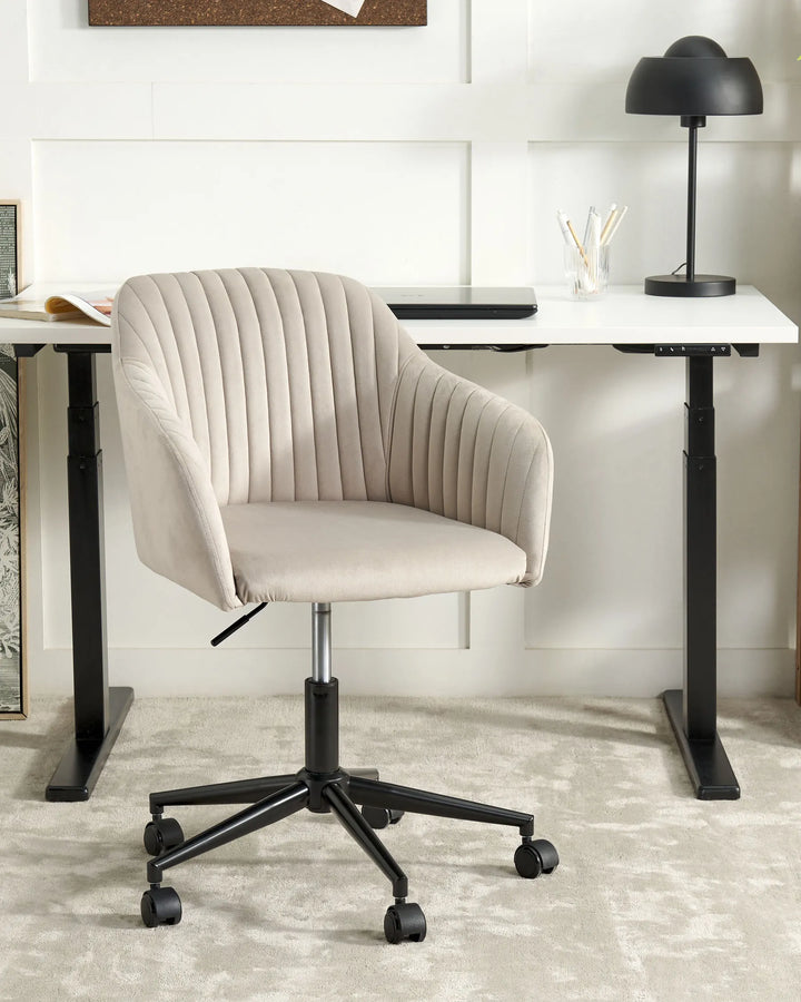 Beige office chair in front of a white desk with a black lamp.