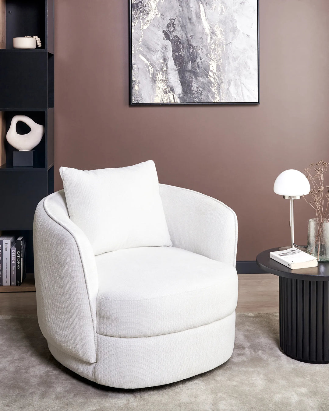 White armchair in a modern living room with a bookshelf and table.