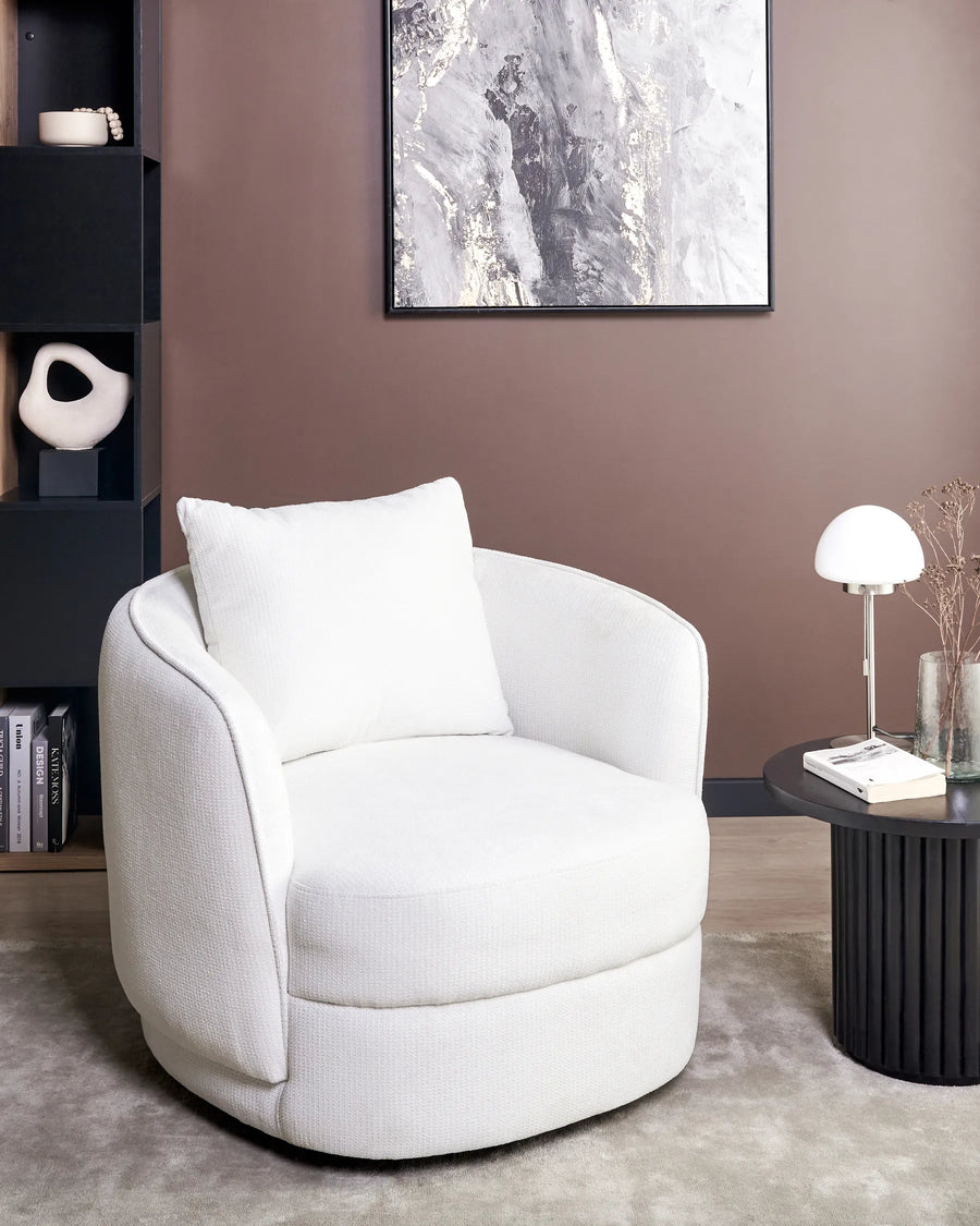 White armchair in a modern living room with a bookshelf and table.